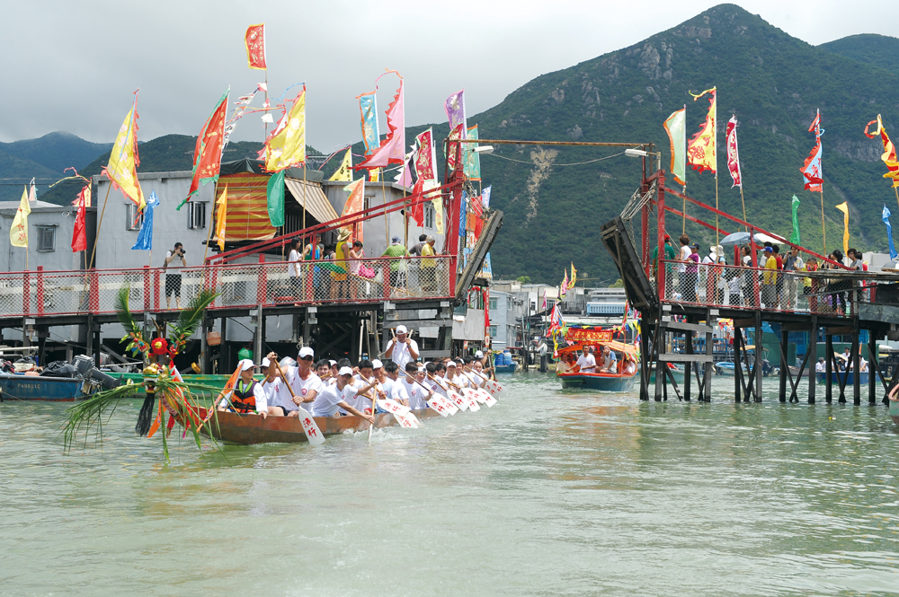 龍船拖著神艇在大澳遊涌，期間穿越大涌橋。