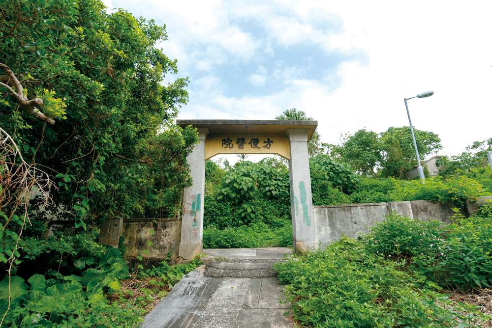 牌坊後面的醫院建築，現今雜草叢生。